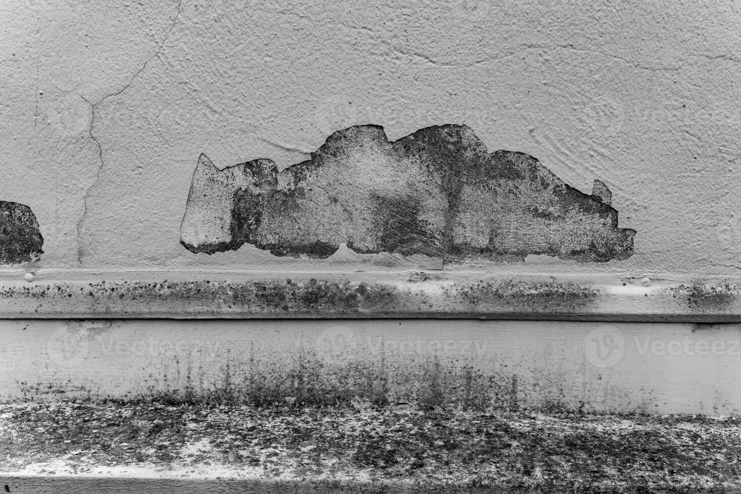 Detail of weathered wall surface showing peeling paint and texture in an urban environment during daylight hours photo