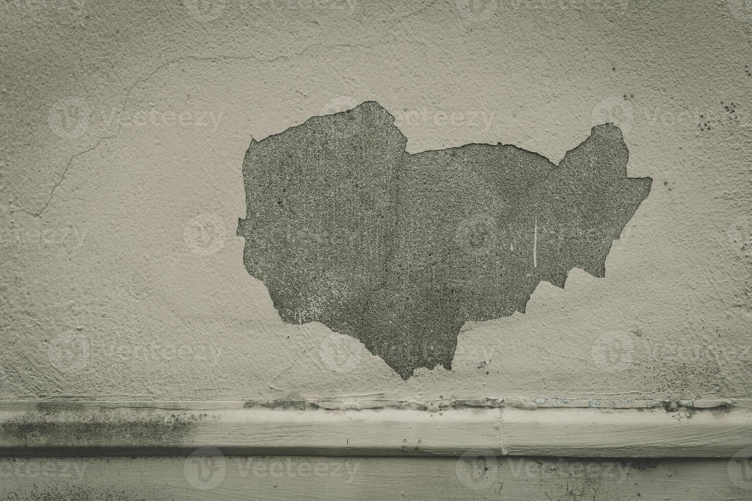 Wall art effect created by a peeling layer of paint revealing an abstract shape on a textured surface in urban space photo