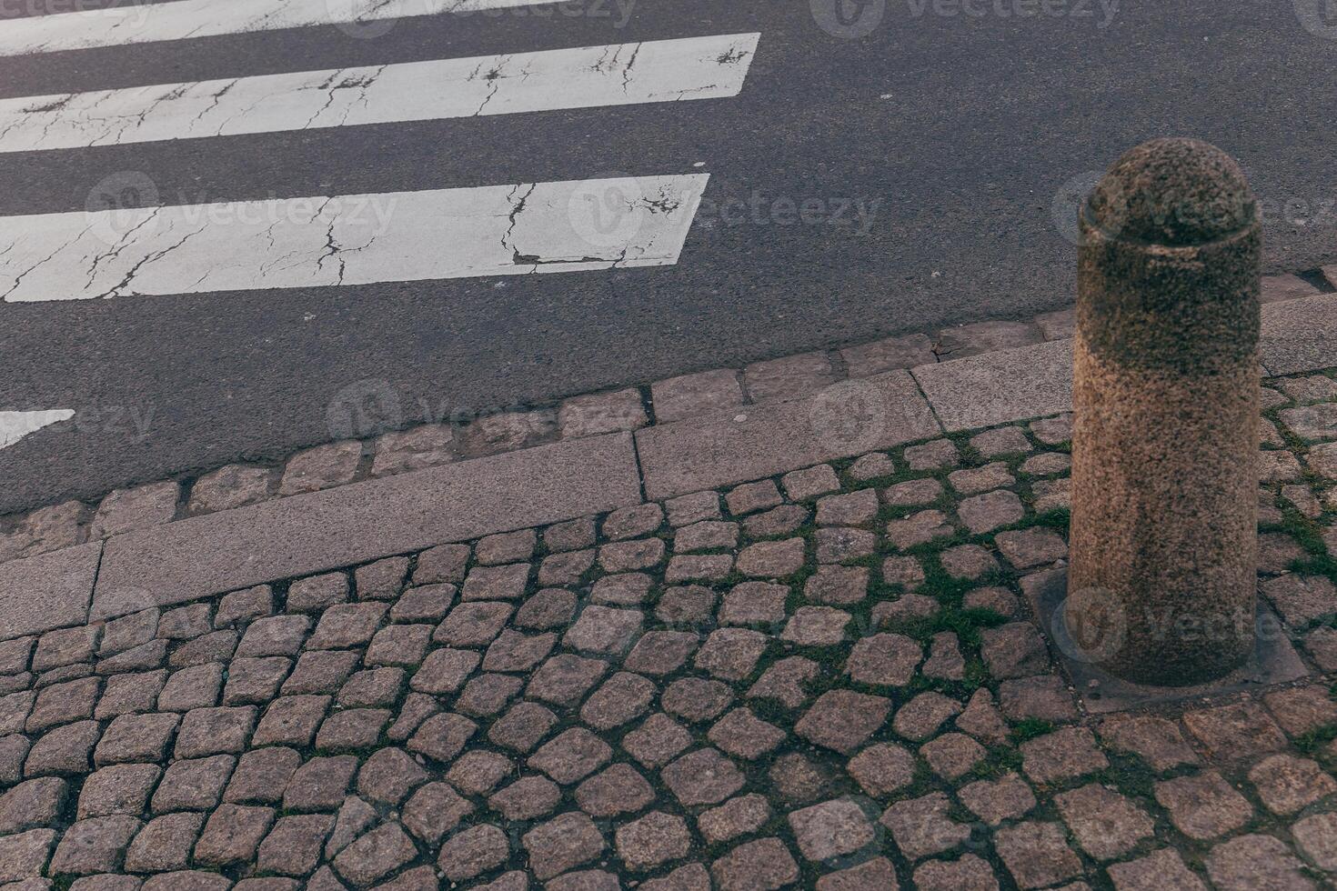 Pedestrian crossing and stone pillar captured in an urban setting during the day photo