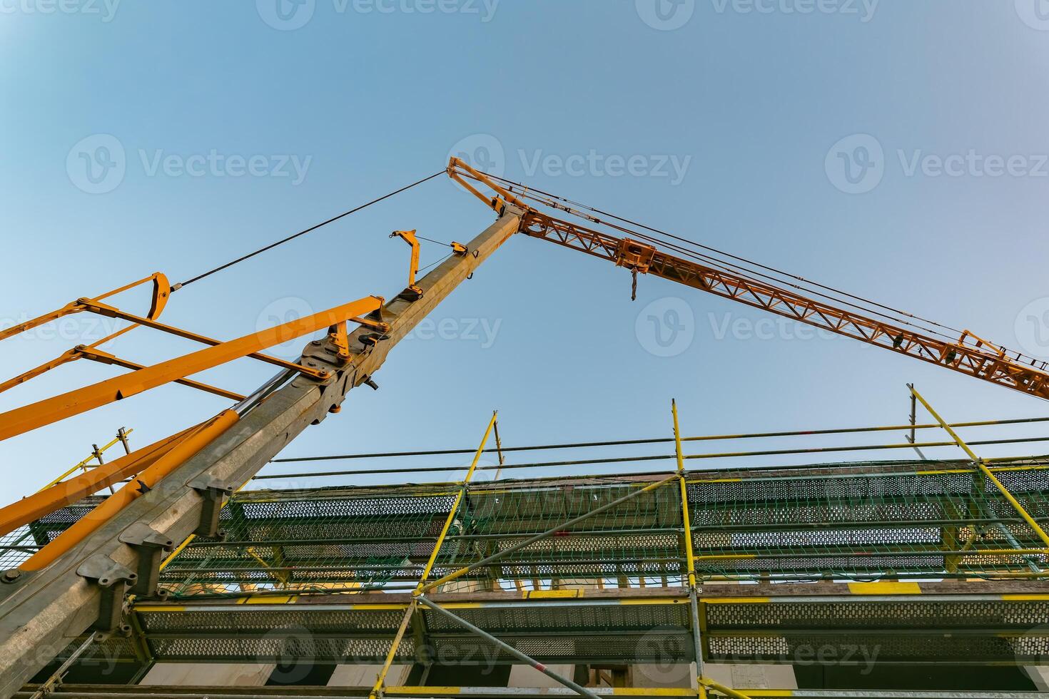 Crane lifting materials for construction work at a building site during bright daylight photo