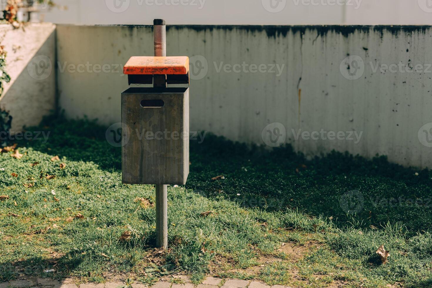 Modern waste bin situated on grassy area in urban park setting during daylight hours photo