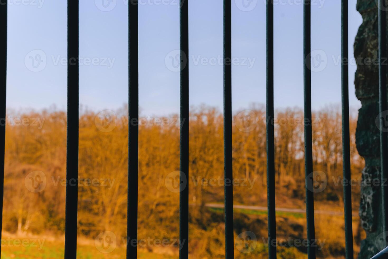 View of a tranquil landscape through metal bars at dusk under a clear sky photo