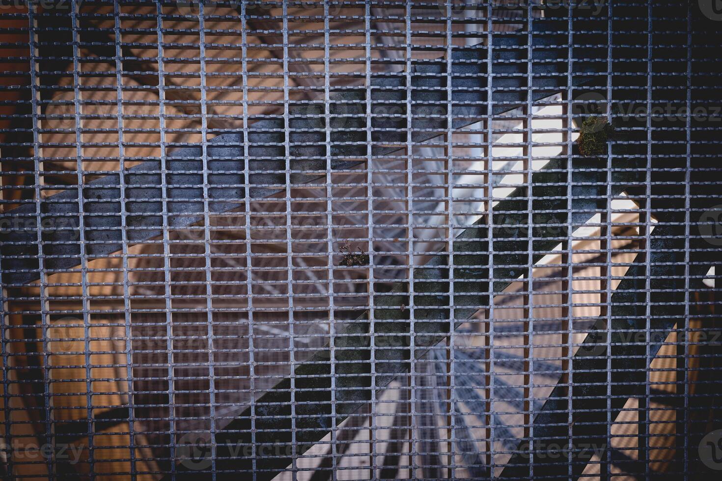 Intricate design of a large ventilation fan seen through a metal grid at a construction site during the afternoon photo