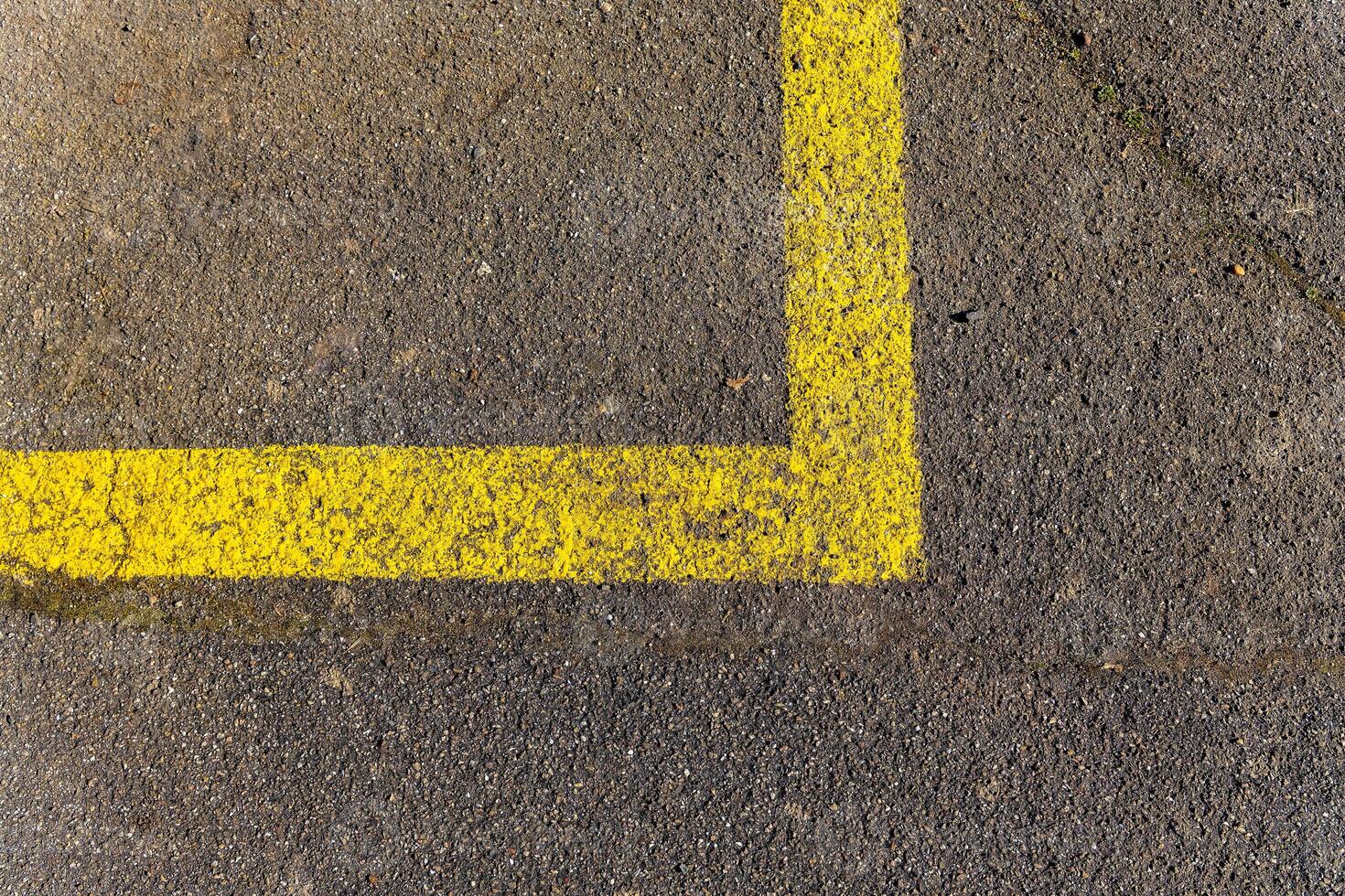 Yellow painted corner line on a concrete surface indicating a parking space near a busy urban area photo
