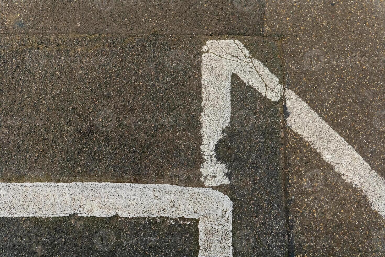 White paint marking on pavement forming an angular design in an urban environment during daylight photo