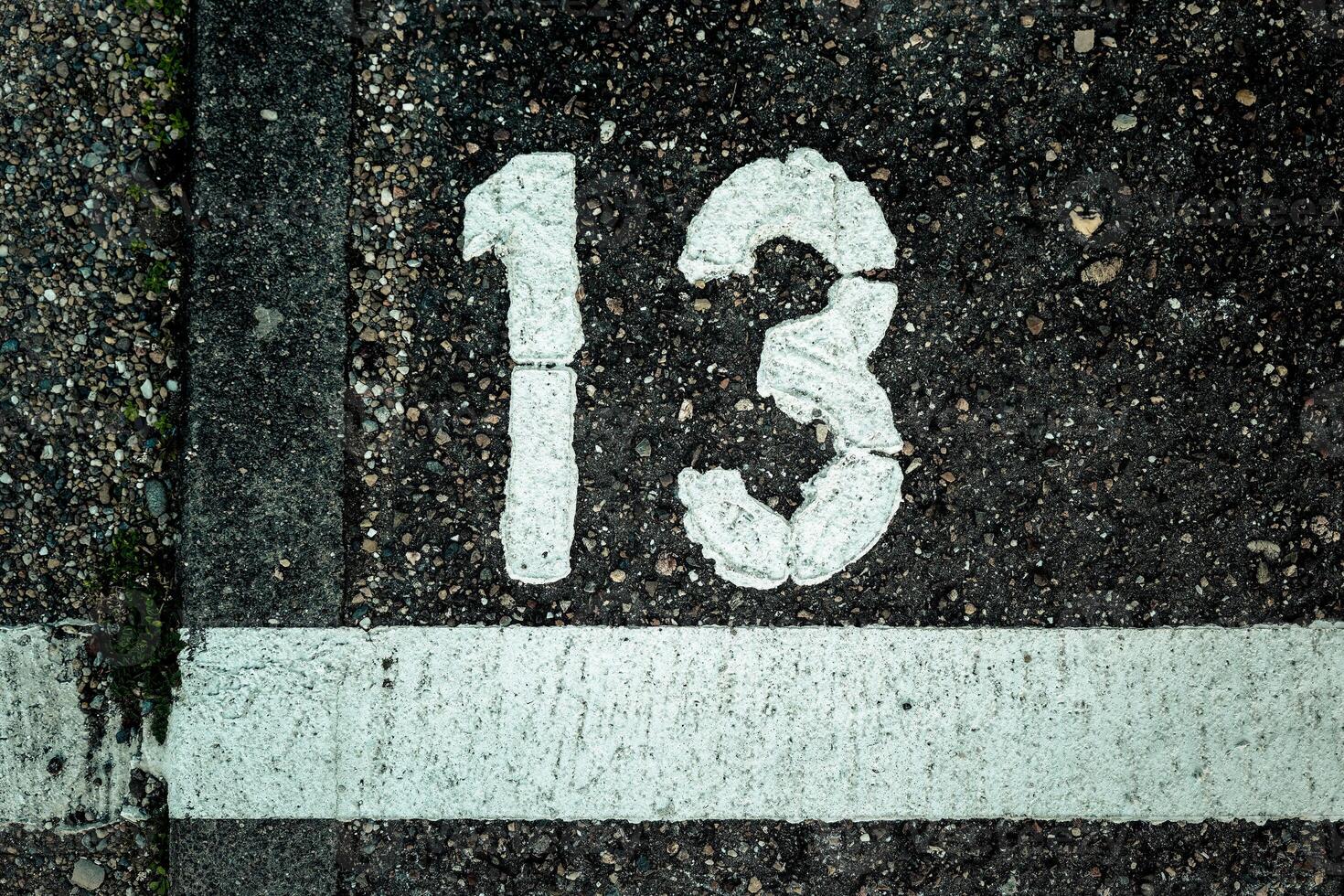 Number 13 marked on a weathered pavement in an urban area showing signs of age and wear photo