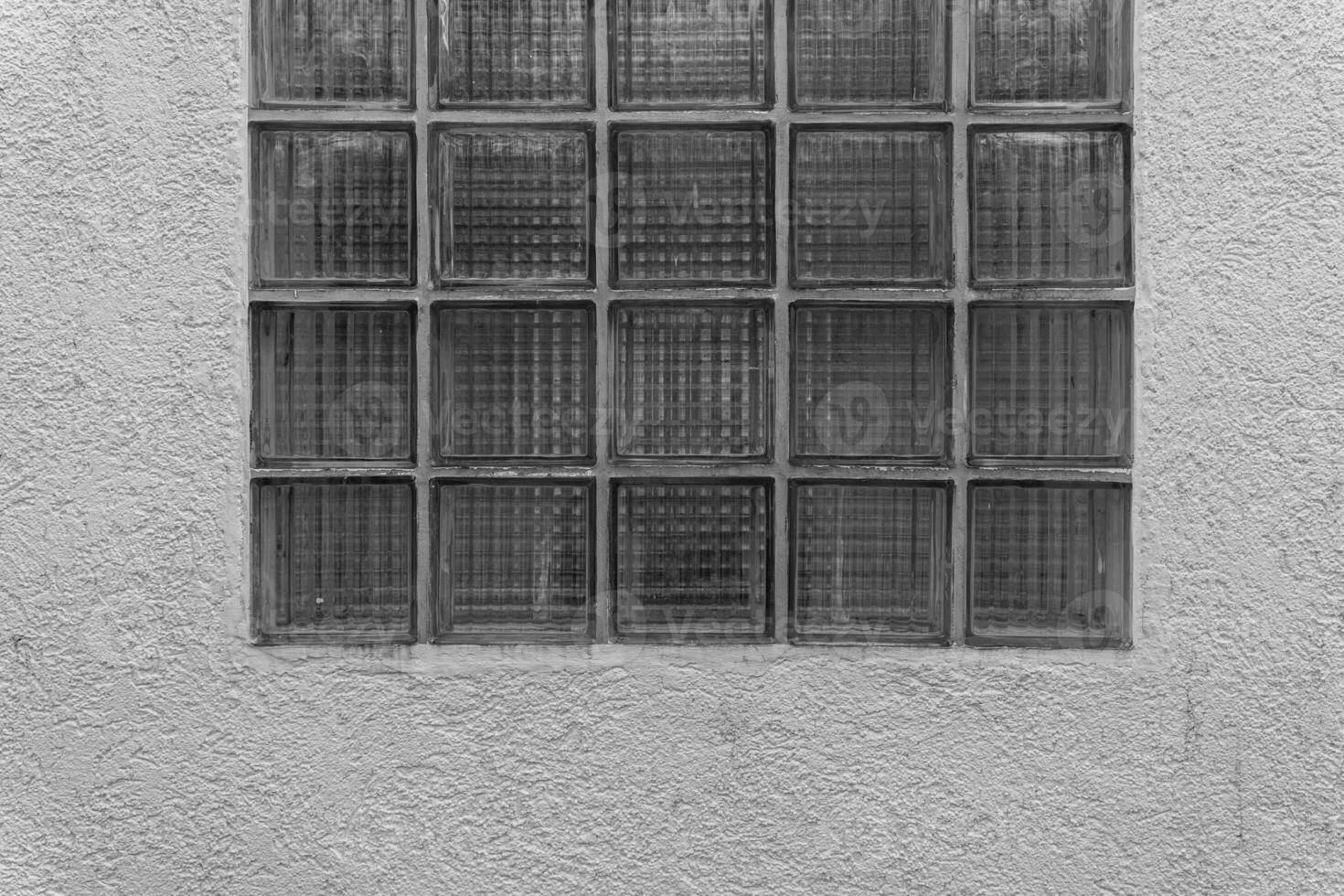 Glass block window on textured wall featuring unique patterns and natural light during the day photo