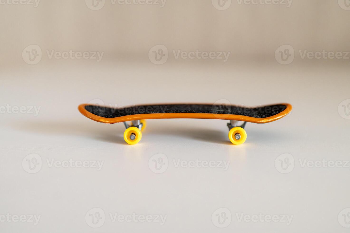 a small fingerboard with yellow wheels on a white surface photo