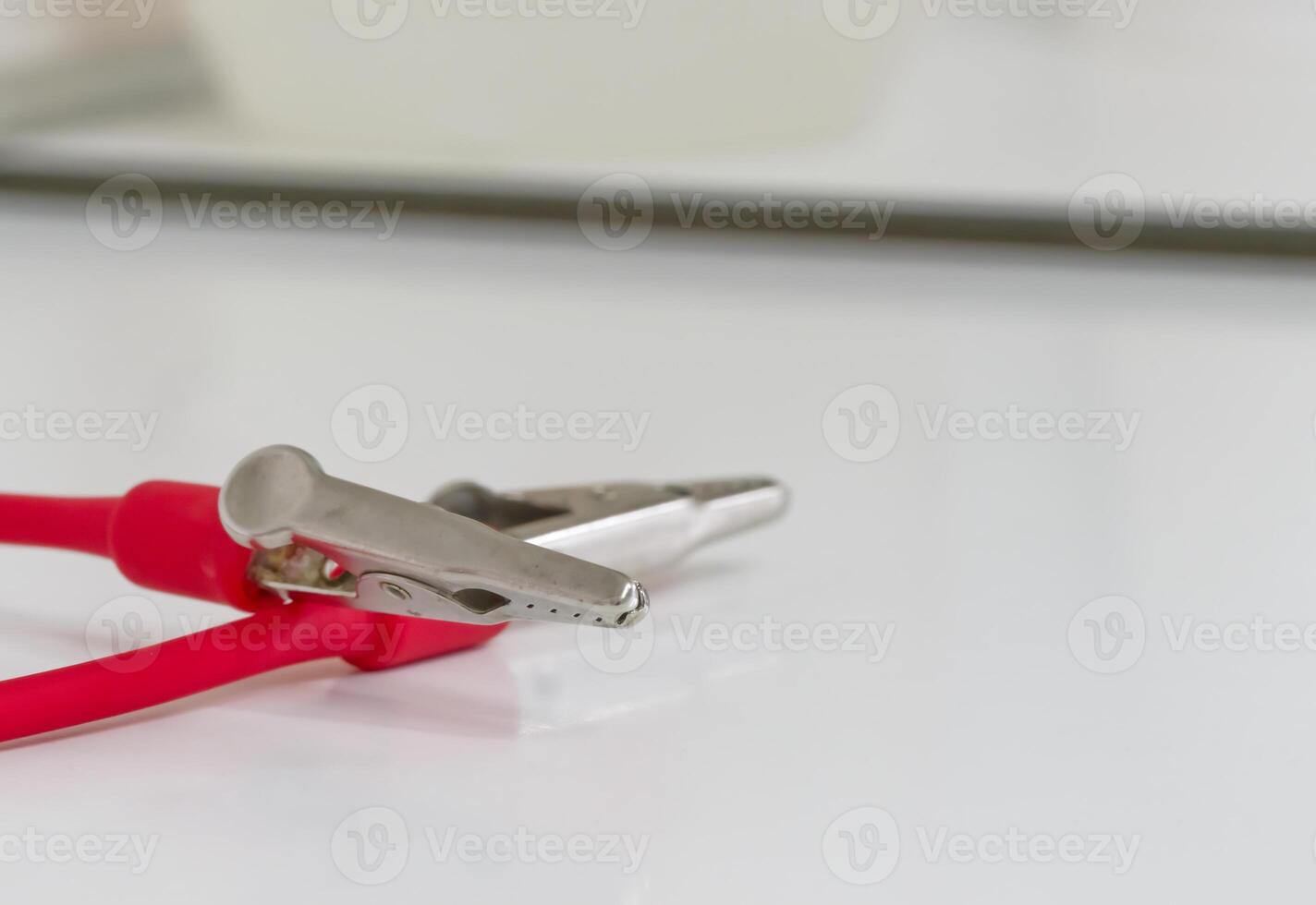 Close-up of a Metal Alligator Clip with Red Insulation photo