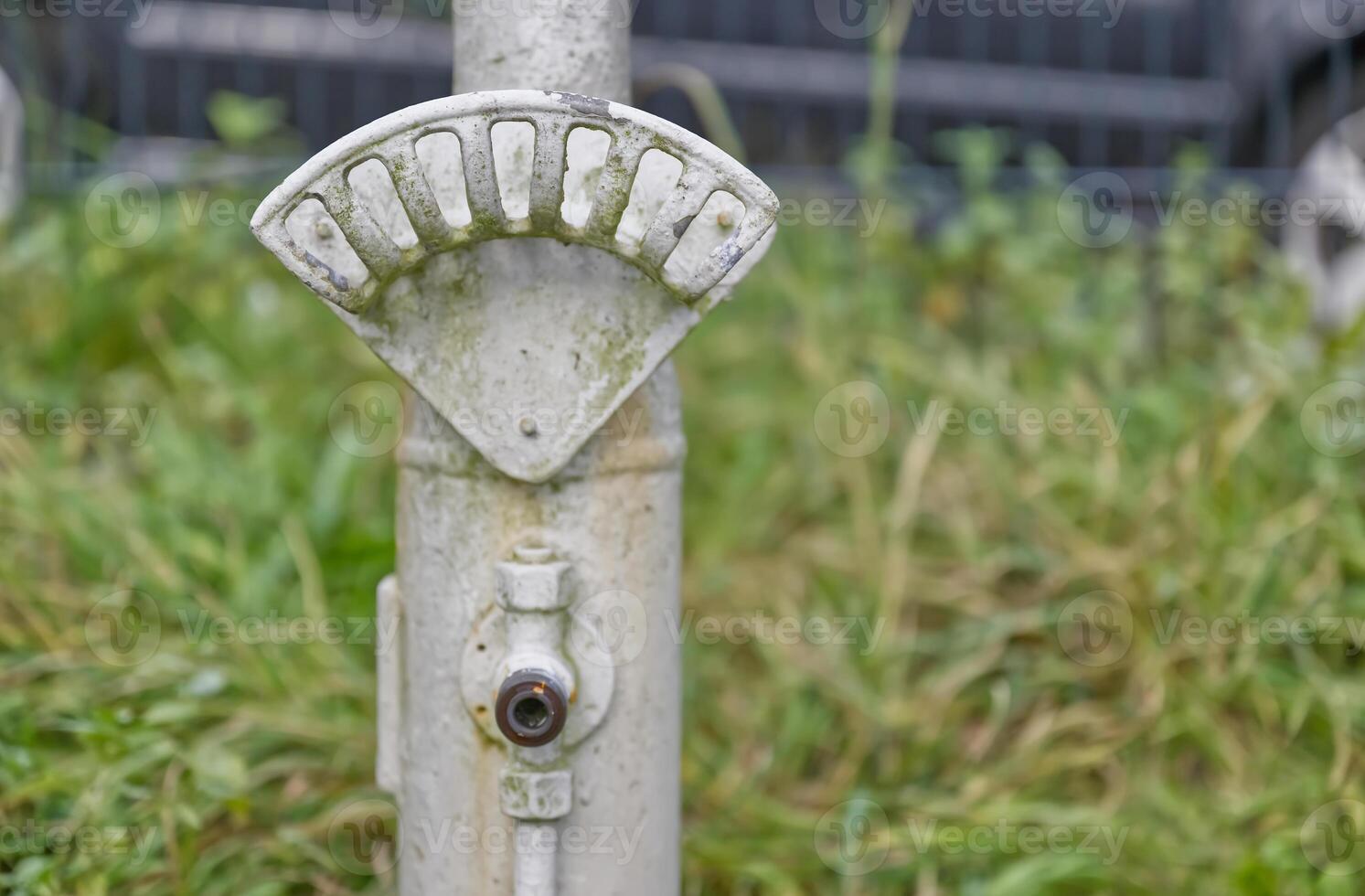 Weathered Metal Pole with Gauge in Grass photo
