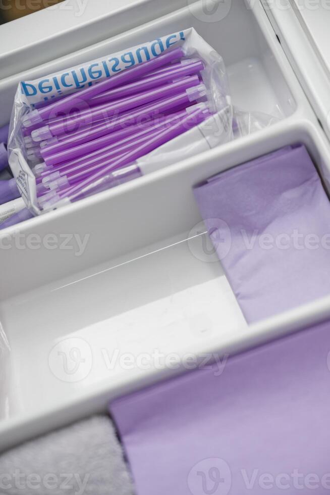 A neatly organized drawer containing purple pens and purple paper. The pens are in a plastic bag, while the paper is folded neatly, showcasing a clean and tidy workspace. photo