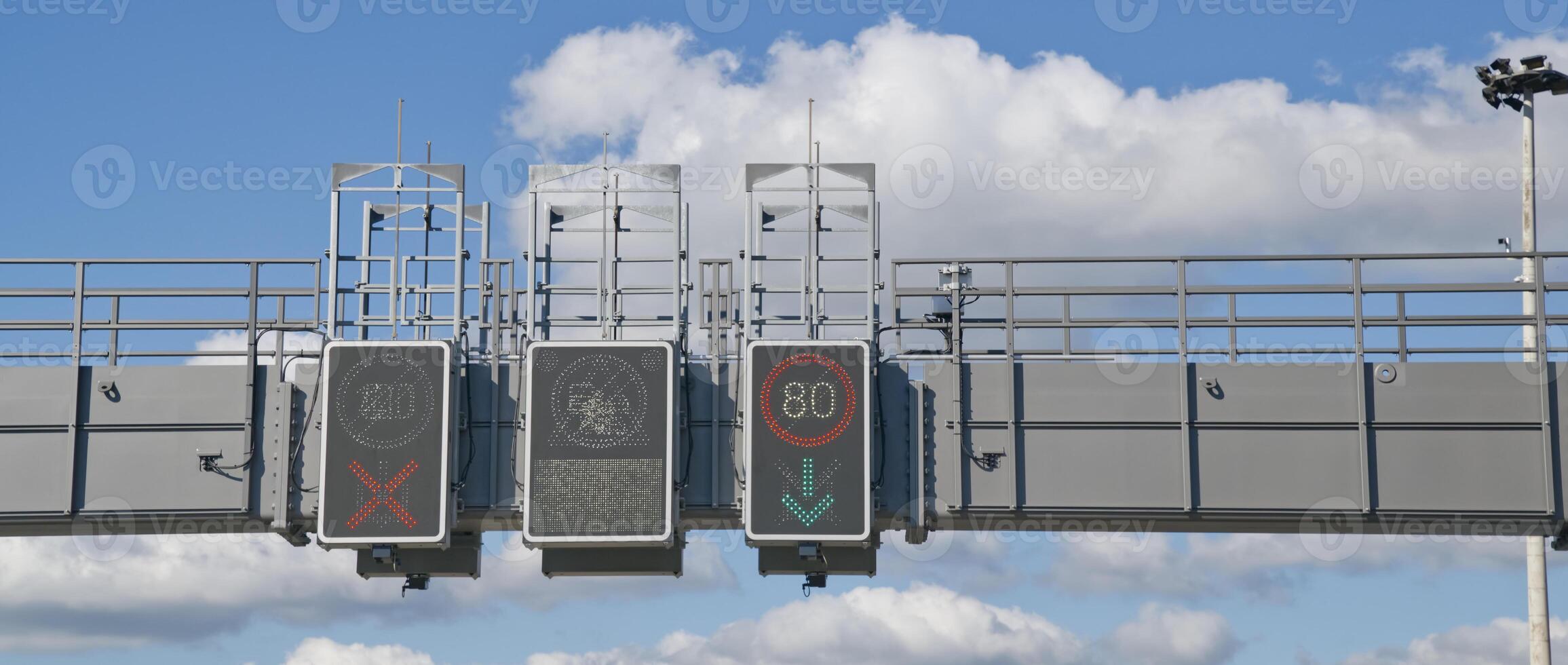 Traffic control signals displaying speed limit and lane usage instructions against a blue sky with clouds. photo