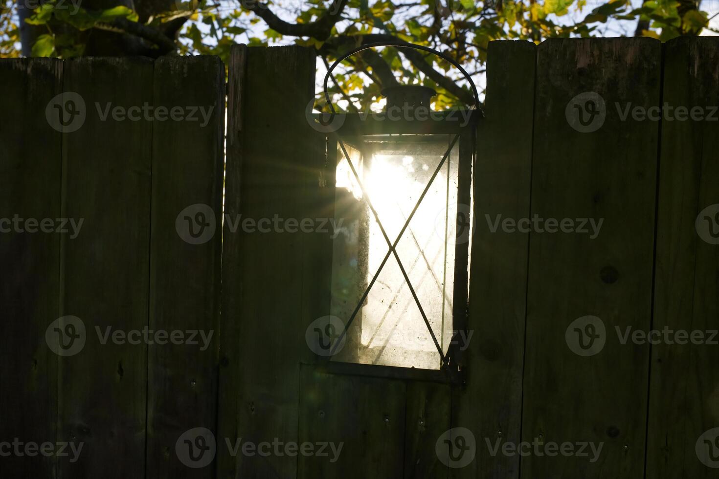 Vintage Lantern on Wooden Fence with Sunlight photo