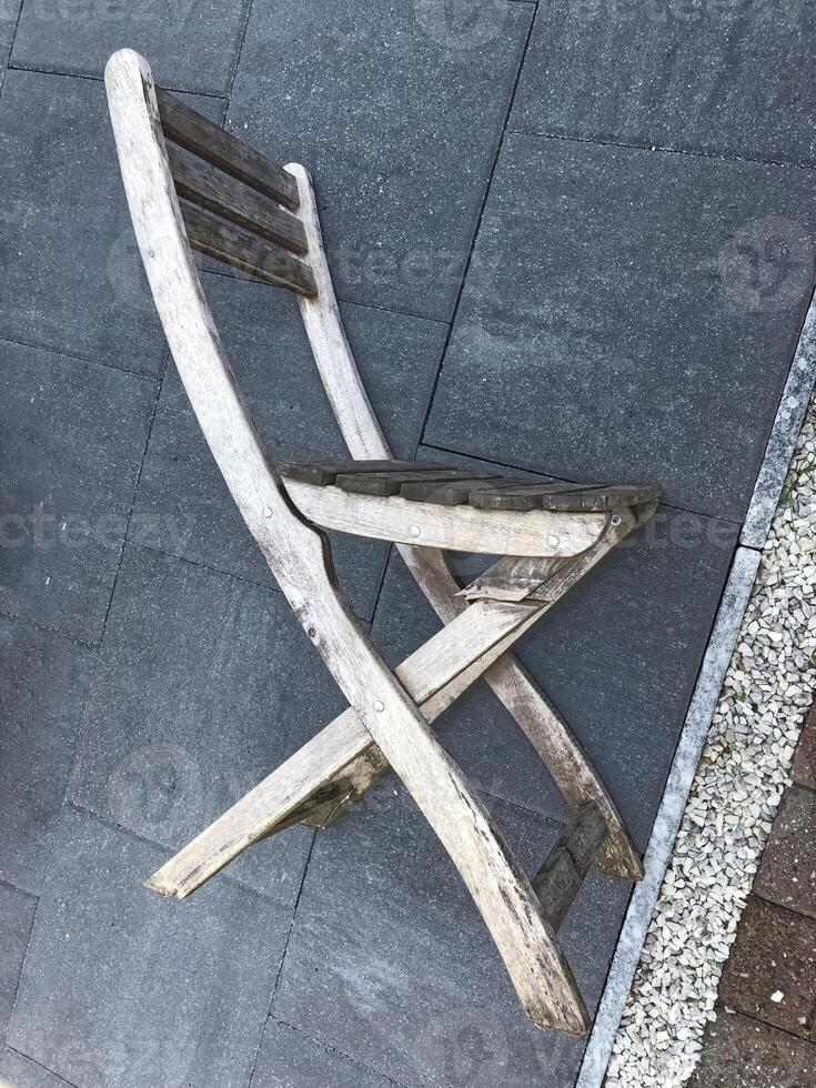 Weathered Wooden Folding Chair on Stone Patio photo
