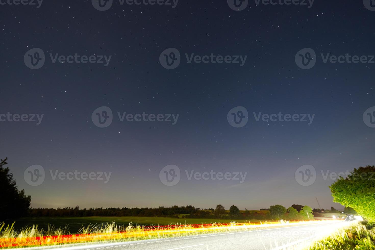 Starry Night Over a Rural Road with Light Trails and Northern Lights photo