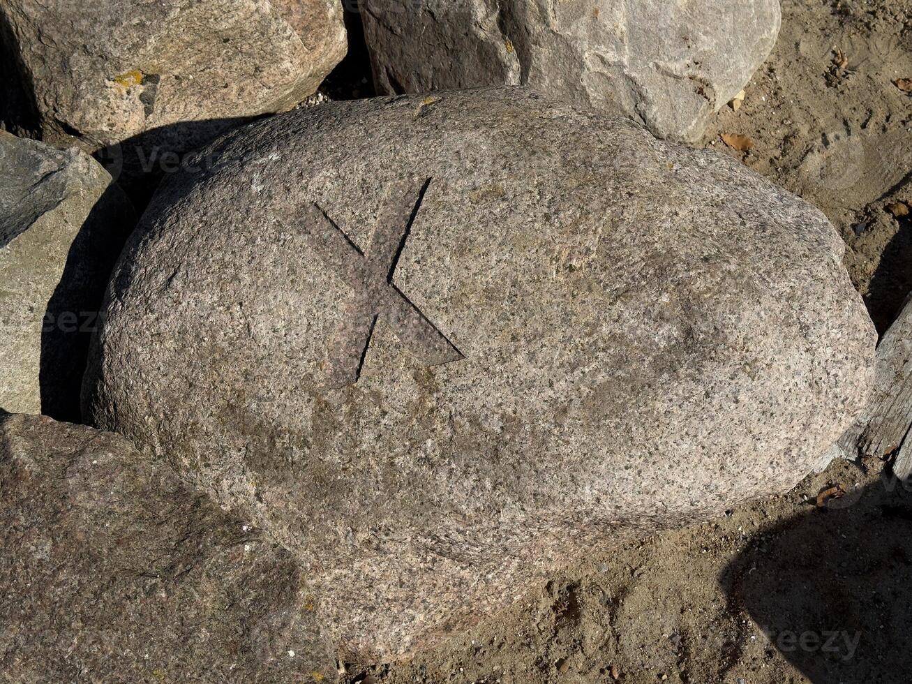Carved X Symbol on a Weathered Rock photo