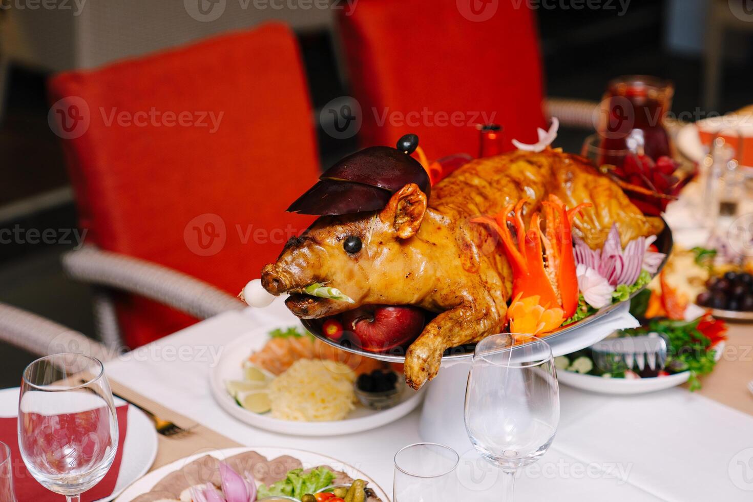Roasted little pig lies on a platter in a restaurant next to snacks photo