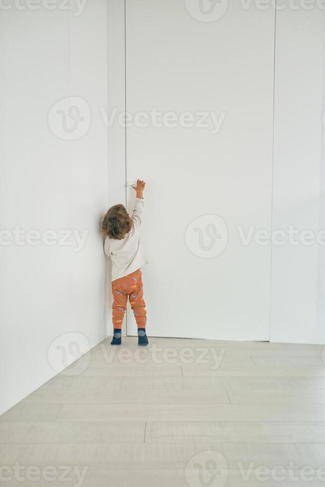 Unrecognizable toddler reaching for doorknob at home photo