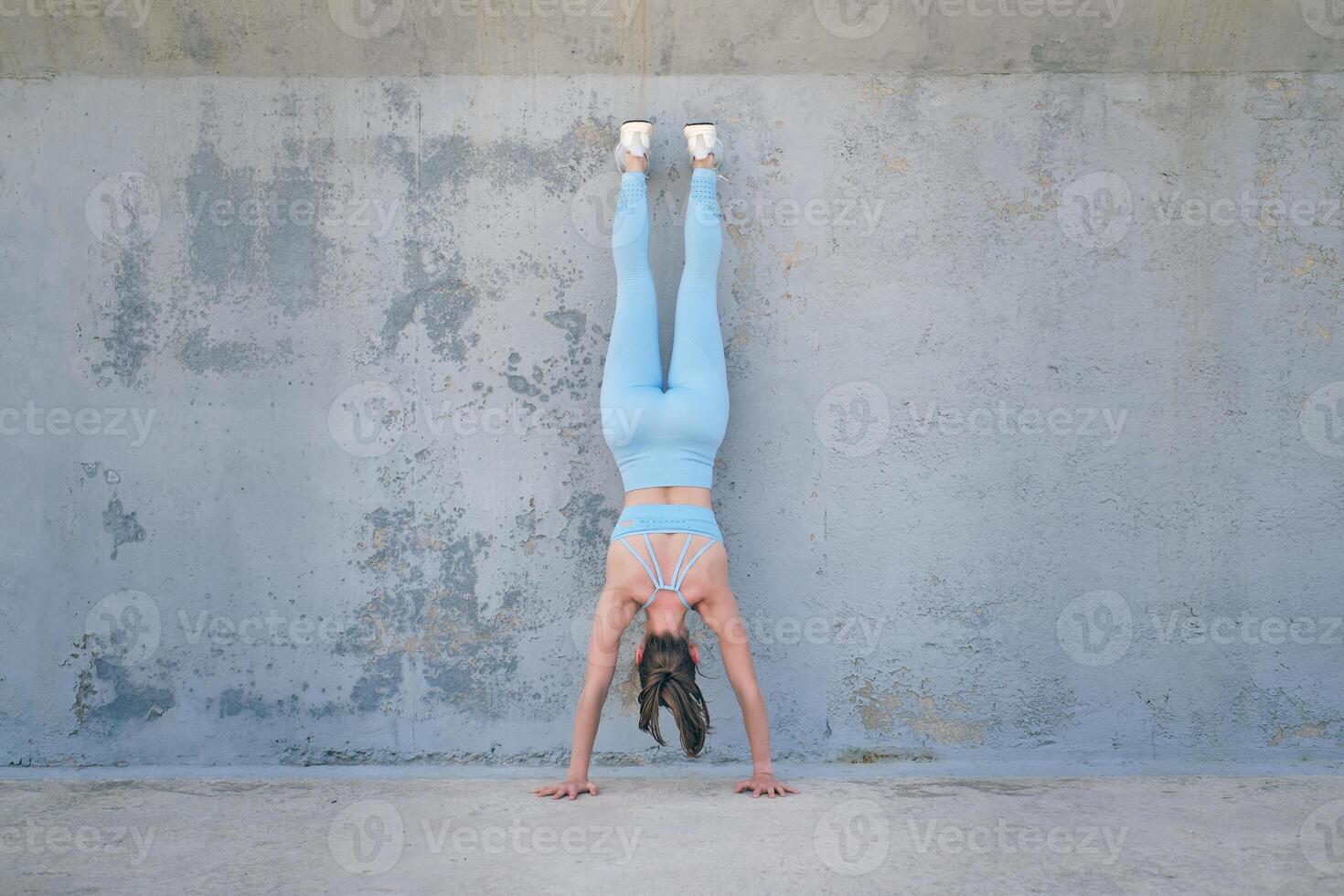 Anonymous athlete standing on hands against rough wall photo
