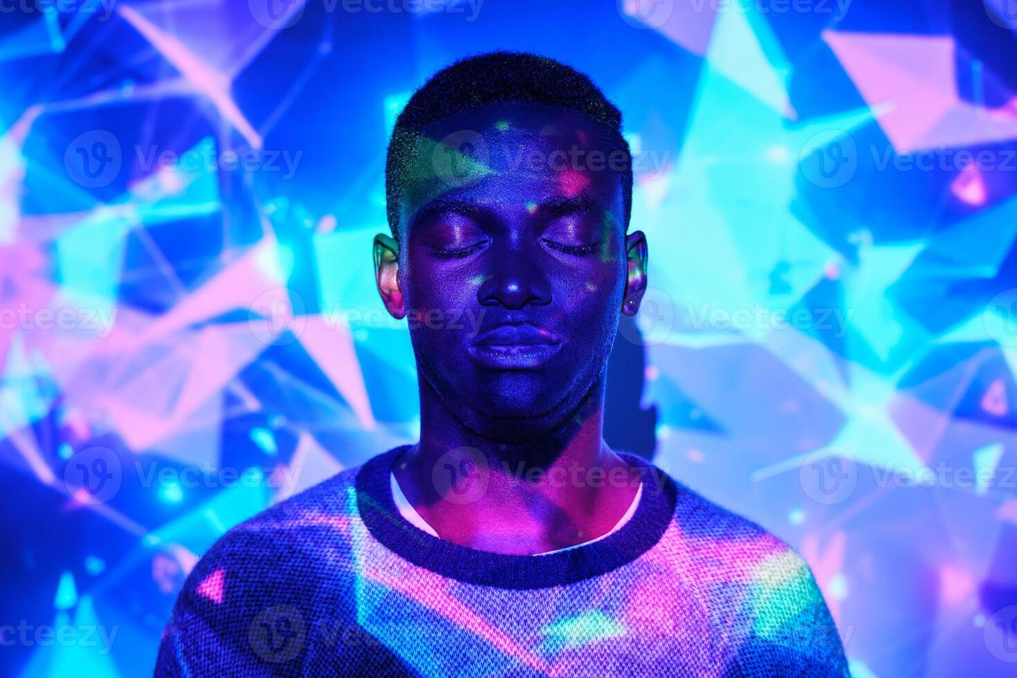 Peaceful black man standing in colorful neon projection photo