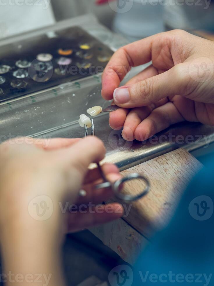 Anonymous dental technician working with artificial teeth photo