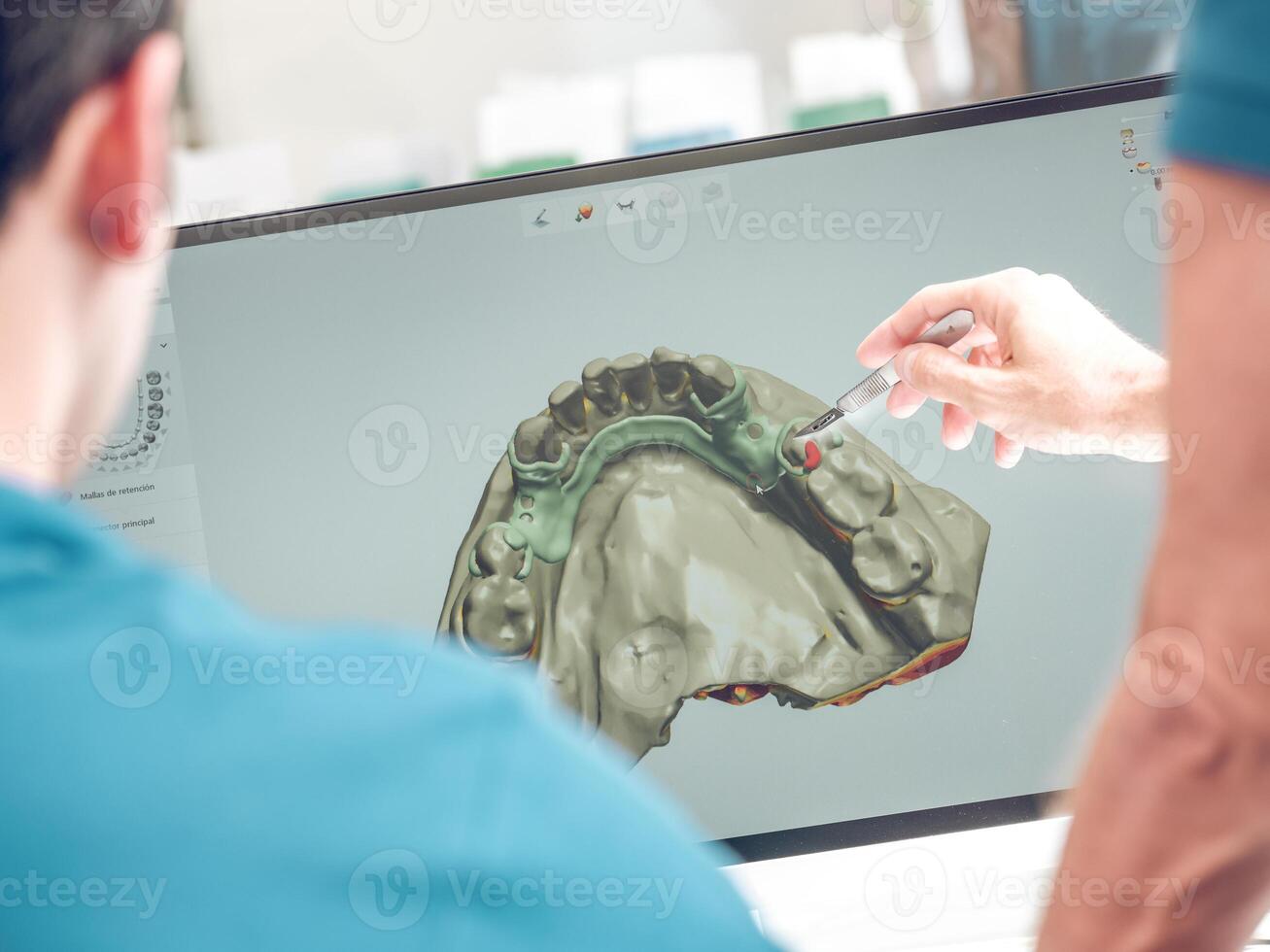 Dentist pointing at monitor with jaw model photo