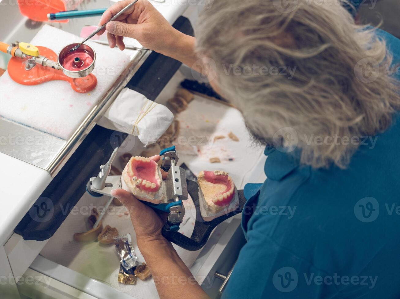 Crop technician holding spatula in flame of dental burner photo