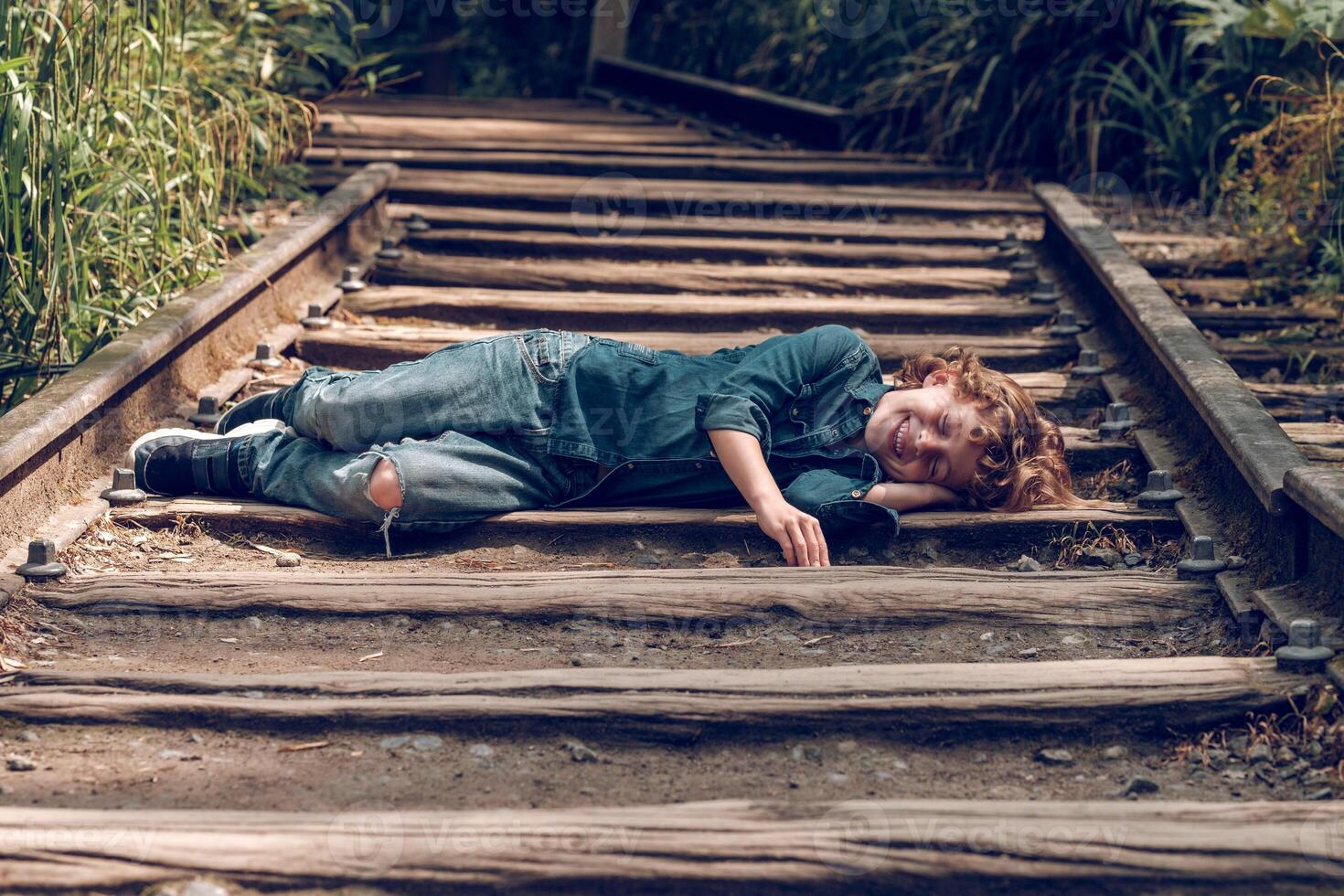 Cheerful boy lying on railroad photo