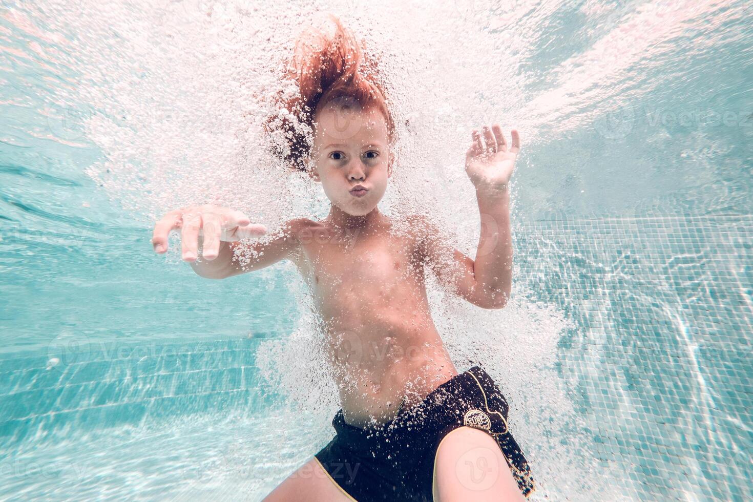 Funny boy swimming underwater in pool photo