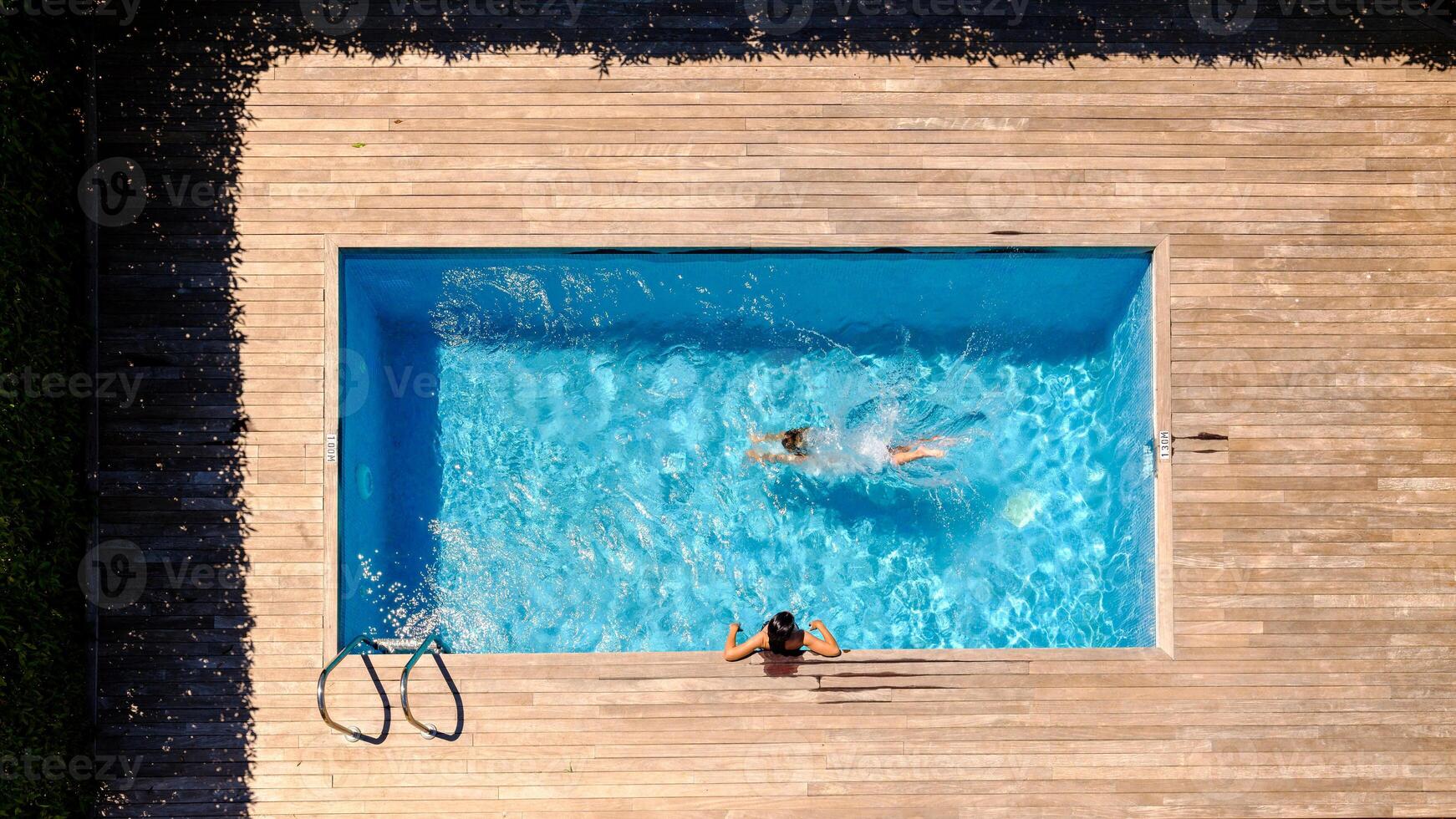 Anonymous people swimming in outdoor pool in yard photo