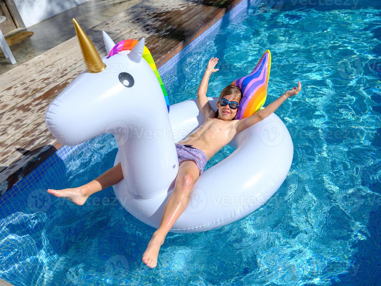 Content kid lying on inflatable ring and floating in swimming po photo