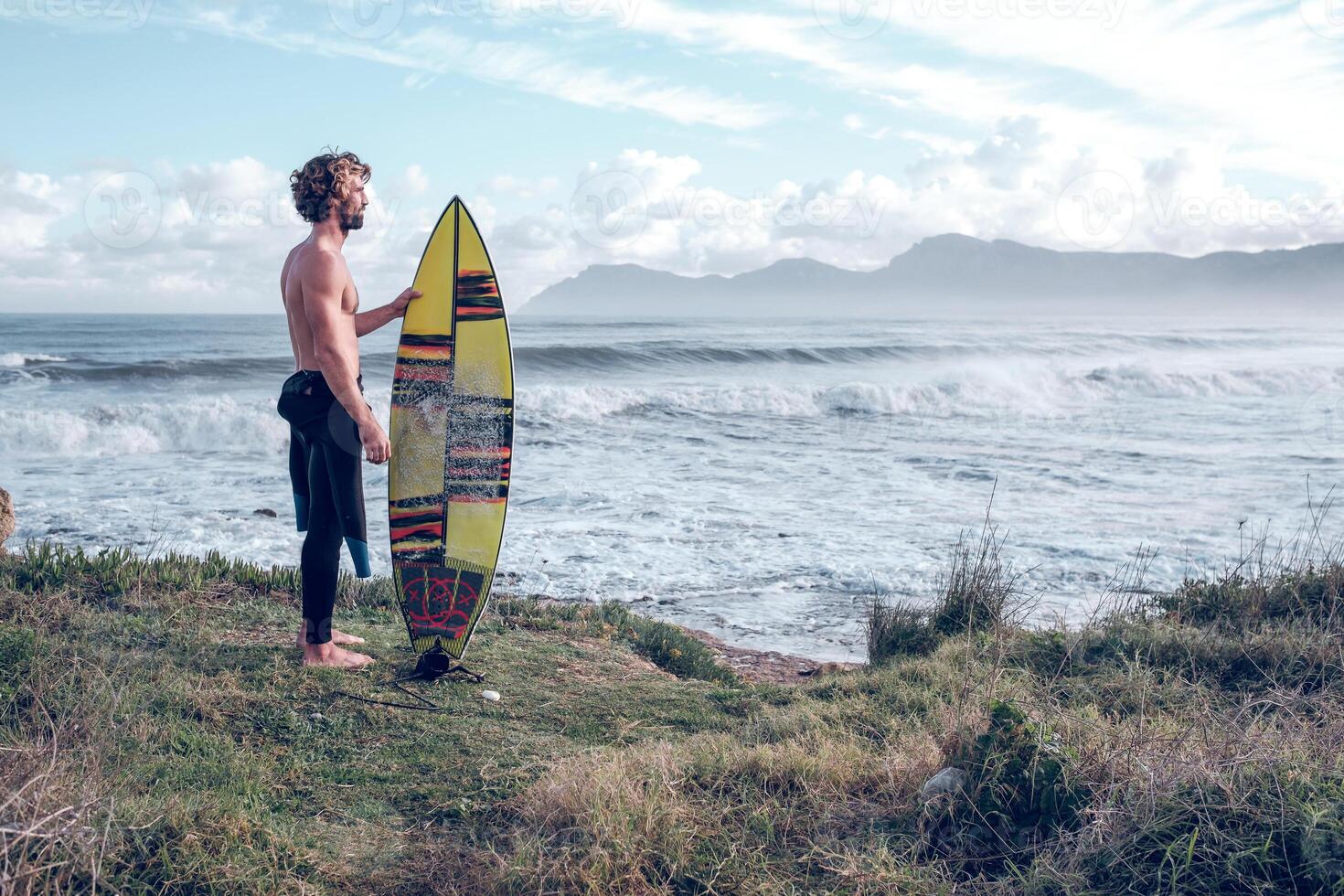 Male surfer with surfboard on coast of waving sea photo