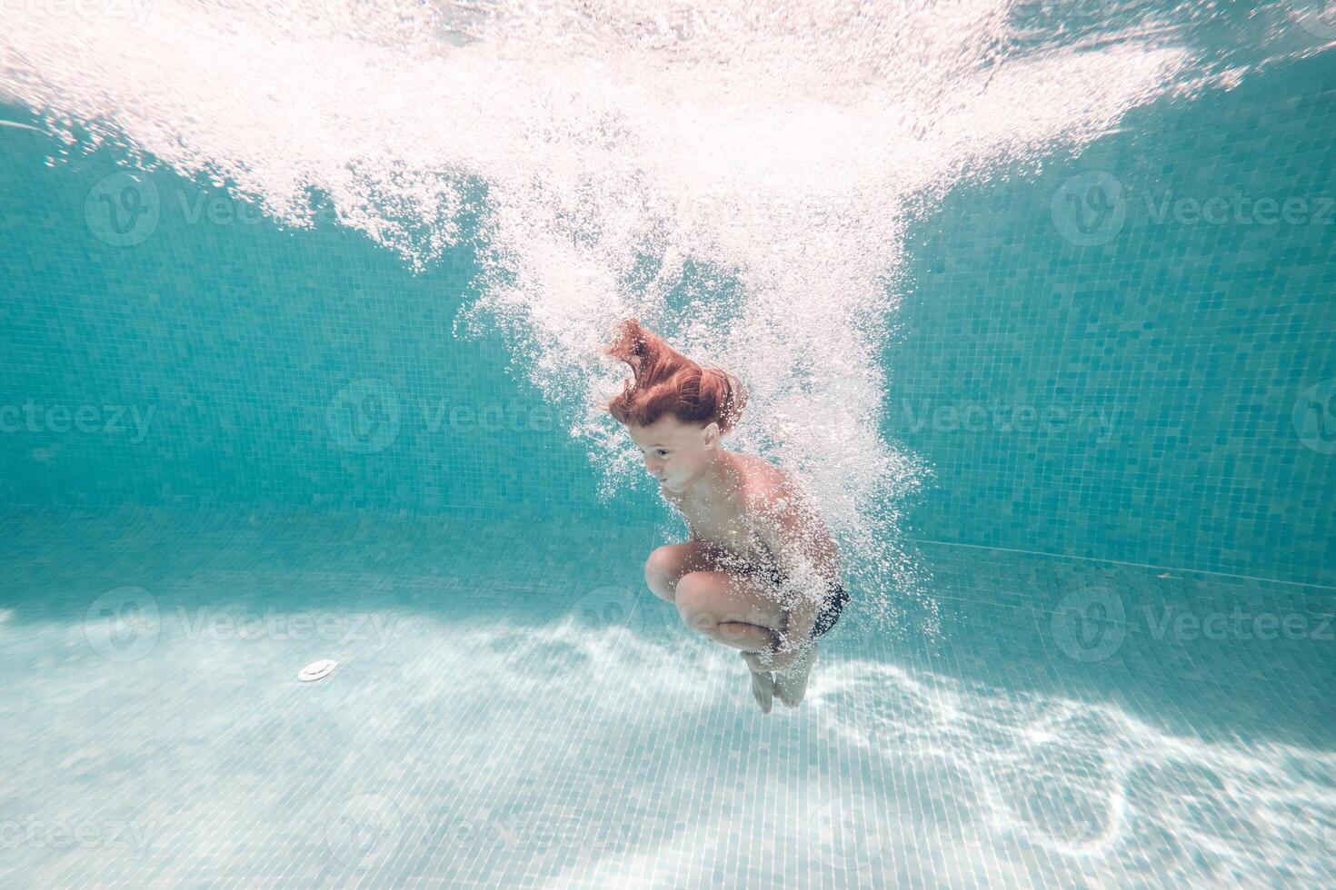 Underwater shot of boy jumping in pool water photo