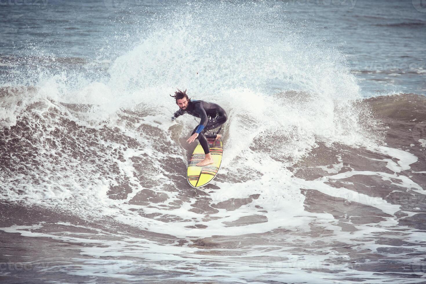 Male surfer on surfboard riding on wave in stormy sea photo