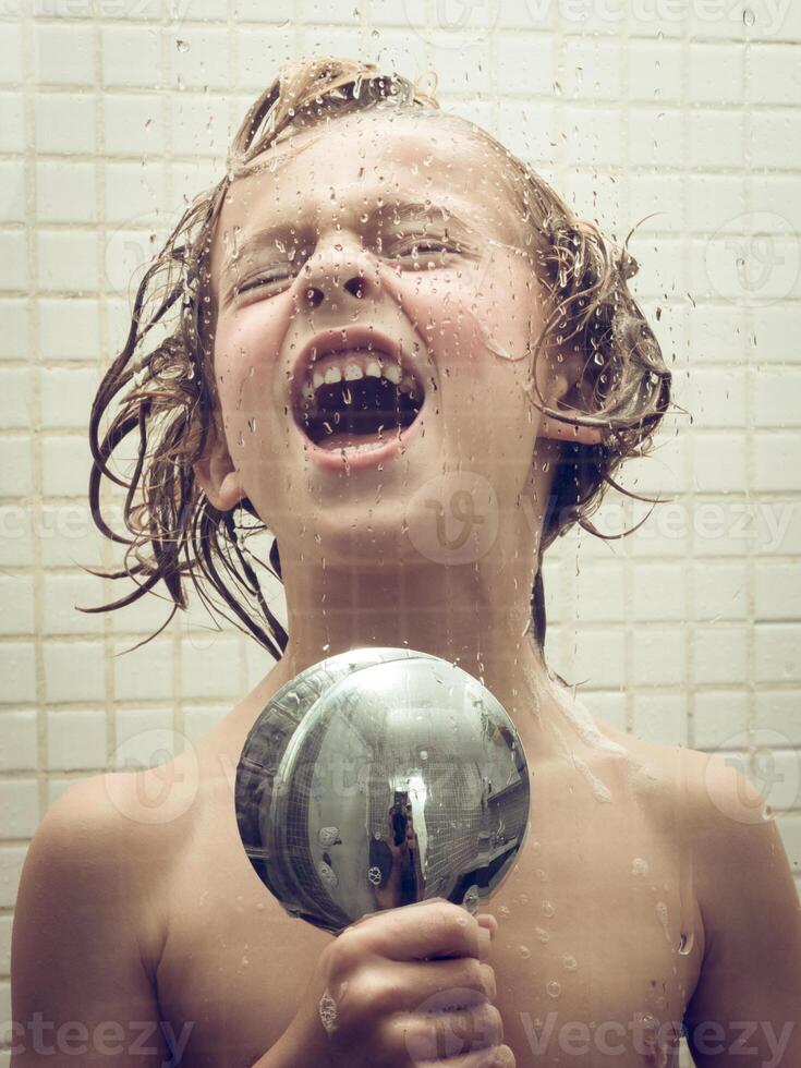 Little child singing with shower head as mic photo