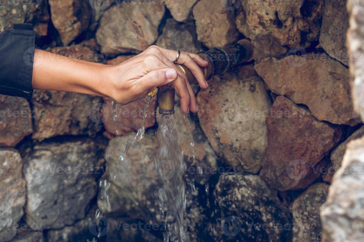 Crop anonymous female opening copper faucet with fresh water photo