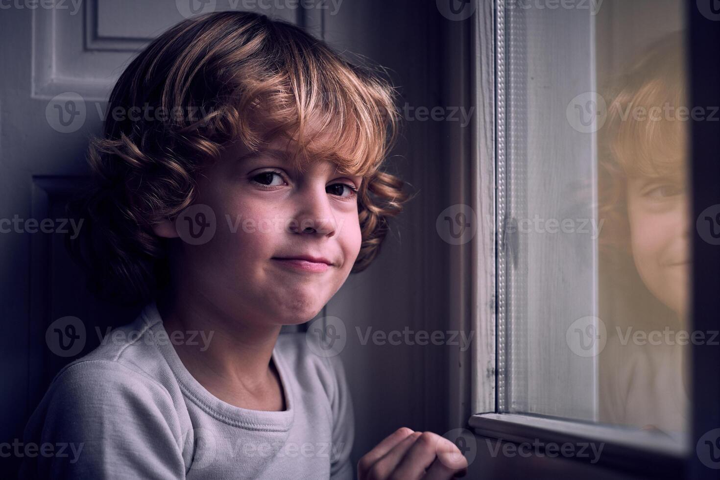 Adorable little boy smiling at camera near window photo