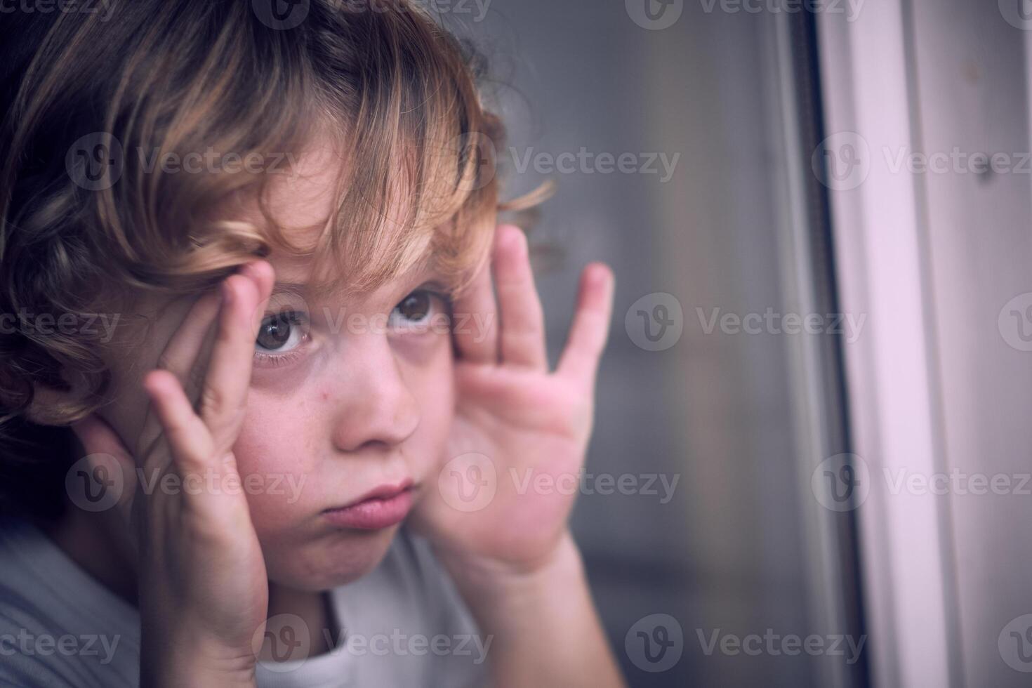 Cute boy looking out window at home photo