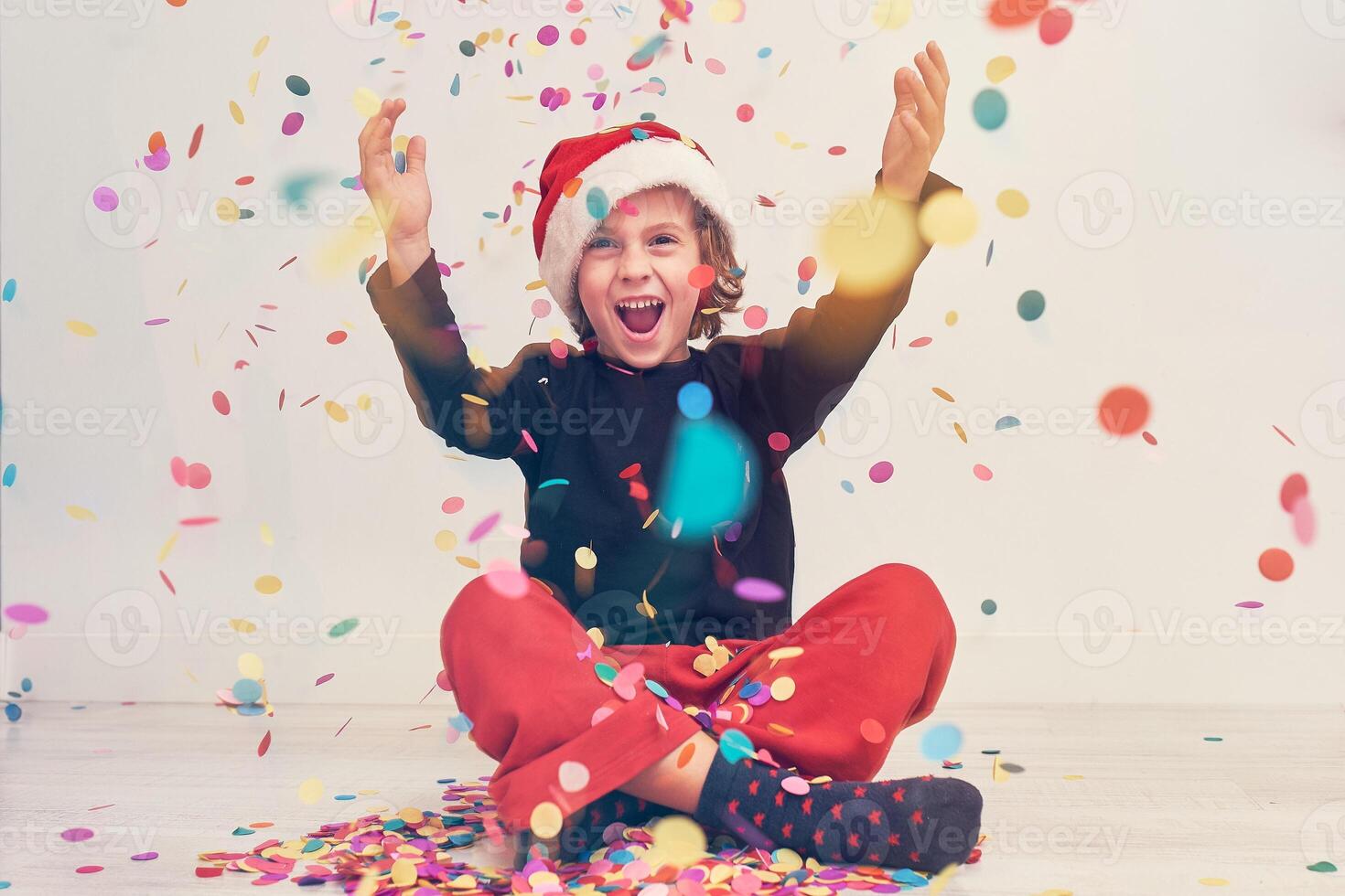 Happy boy in Santa hat under confetti photo