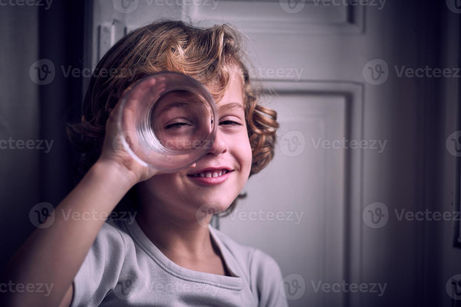 Positive little kid smiling and looking at camera through glass photo