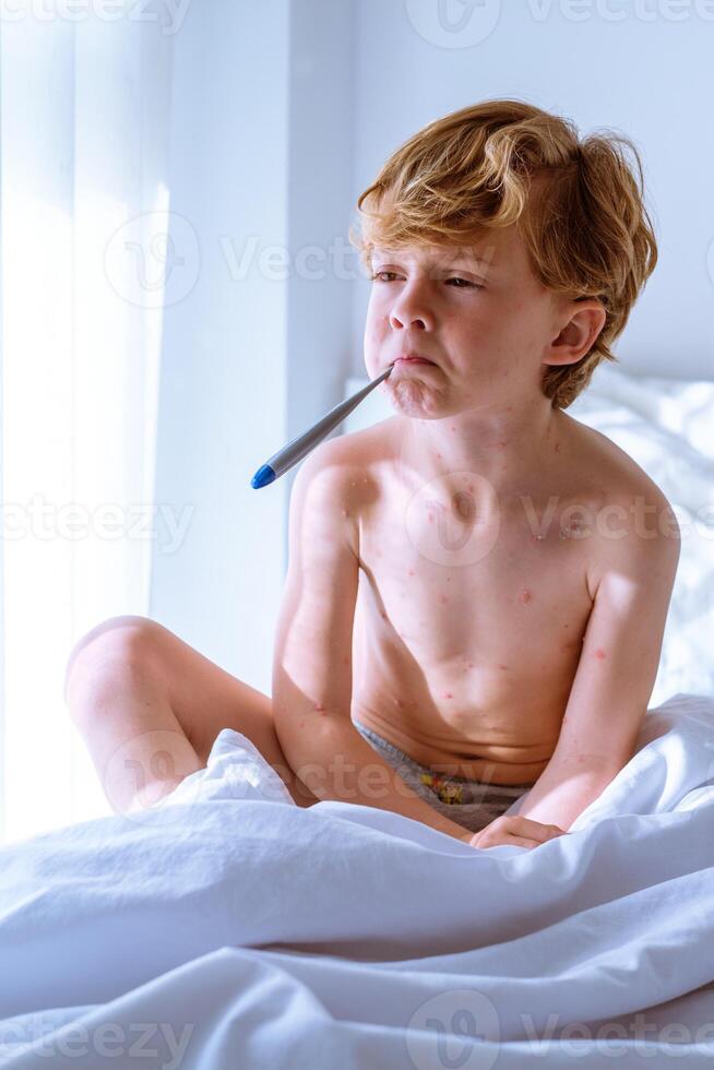 Sick boy measuring temperature in mouth photo