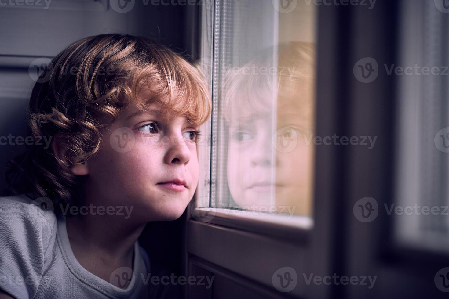 Dreamy cute kid looking out window photo