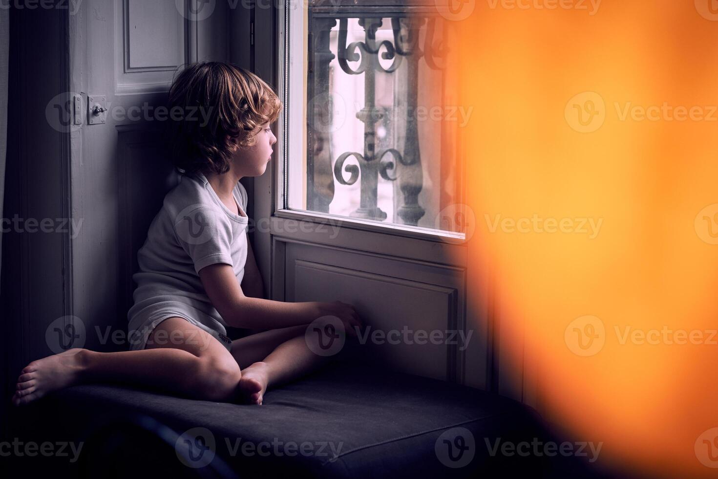 Attentive kid looking through window at home photo