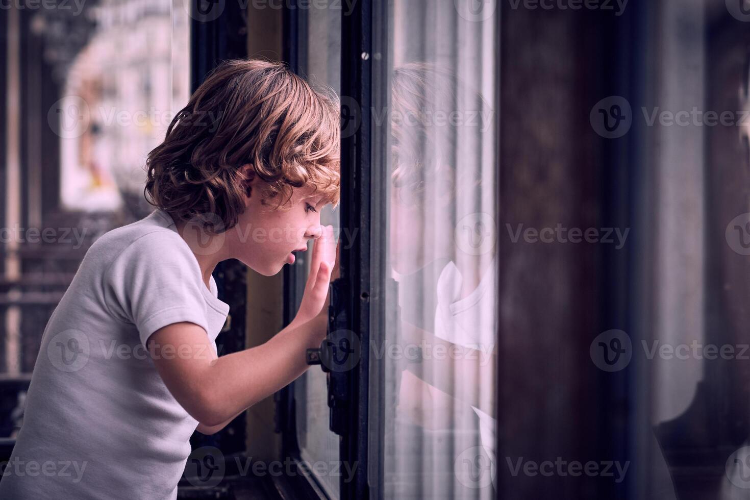 Curious little child looking through window in apartment photo