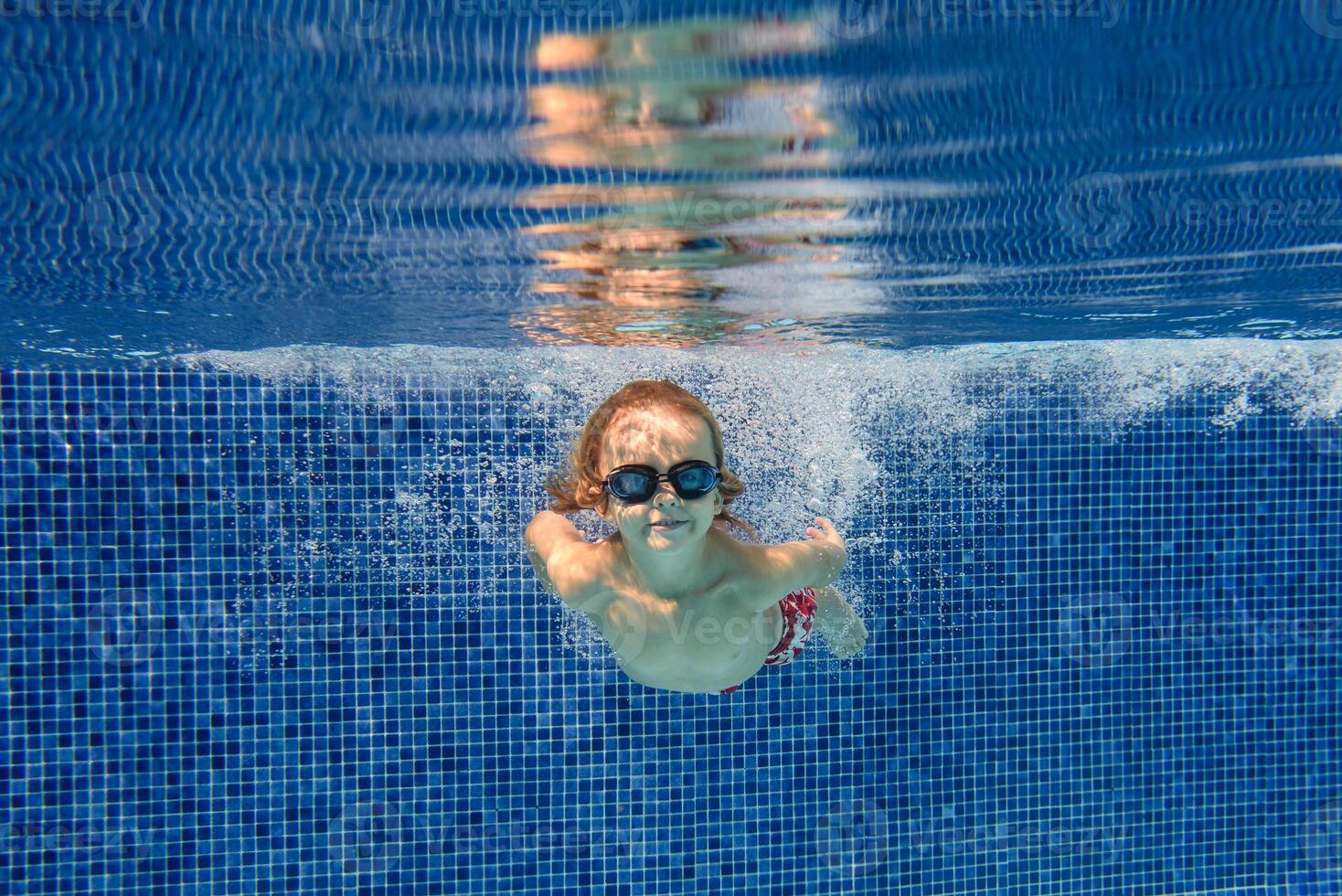 Content boy swimming underwater in pool photo