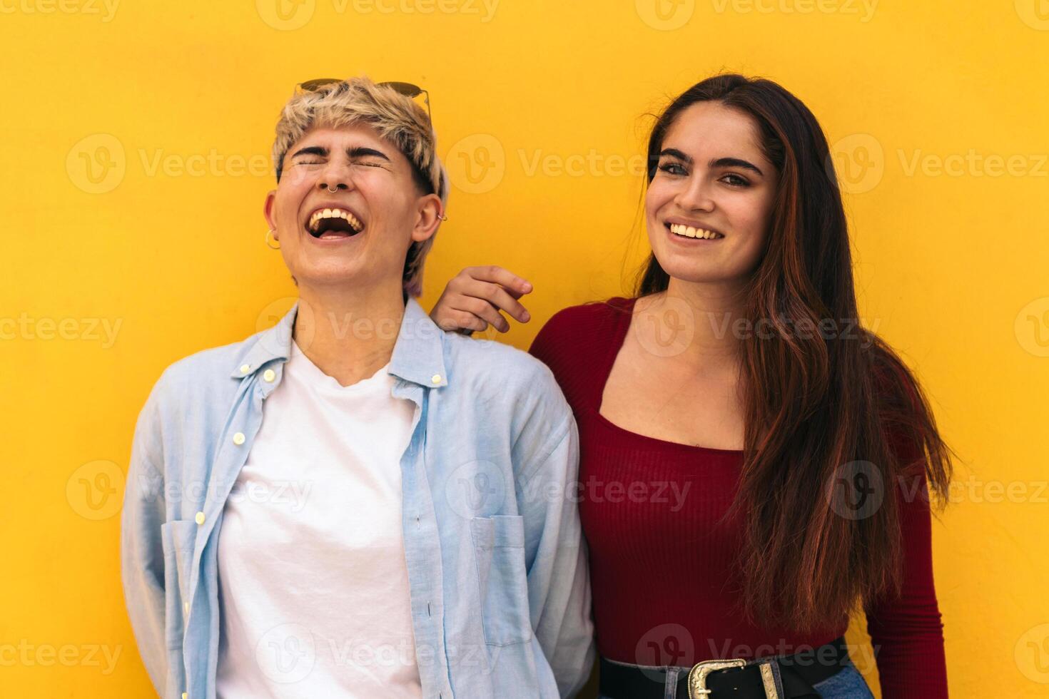 two teenager girls laughing on a yellow background photo