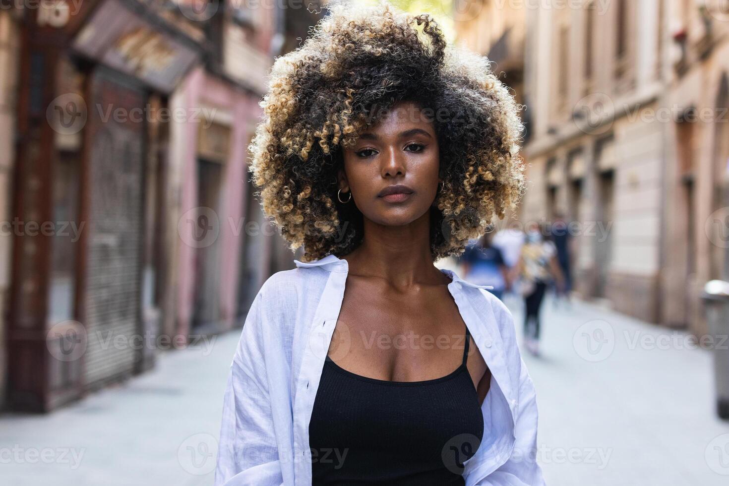 Gorgeous woman with curly hair standing on street photo