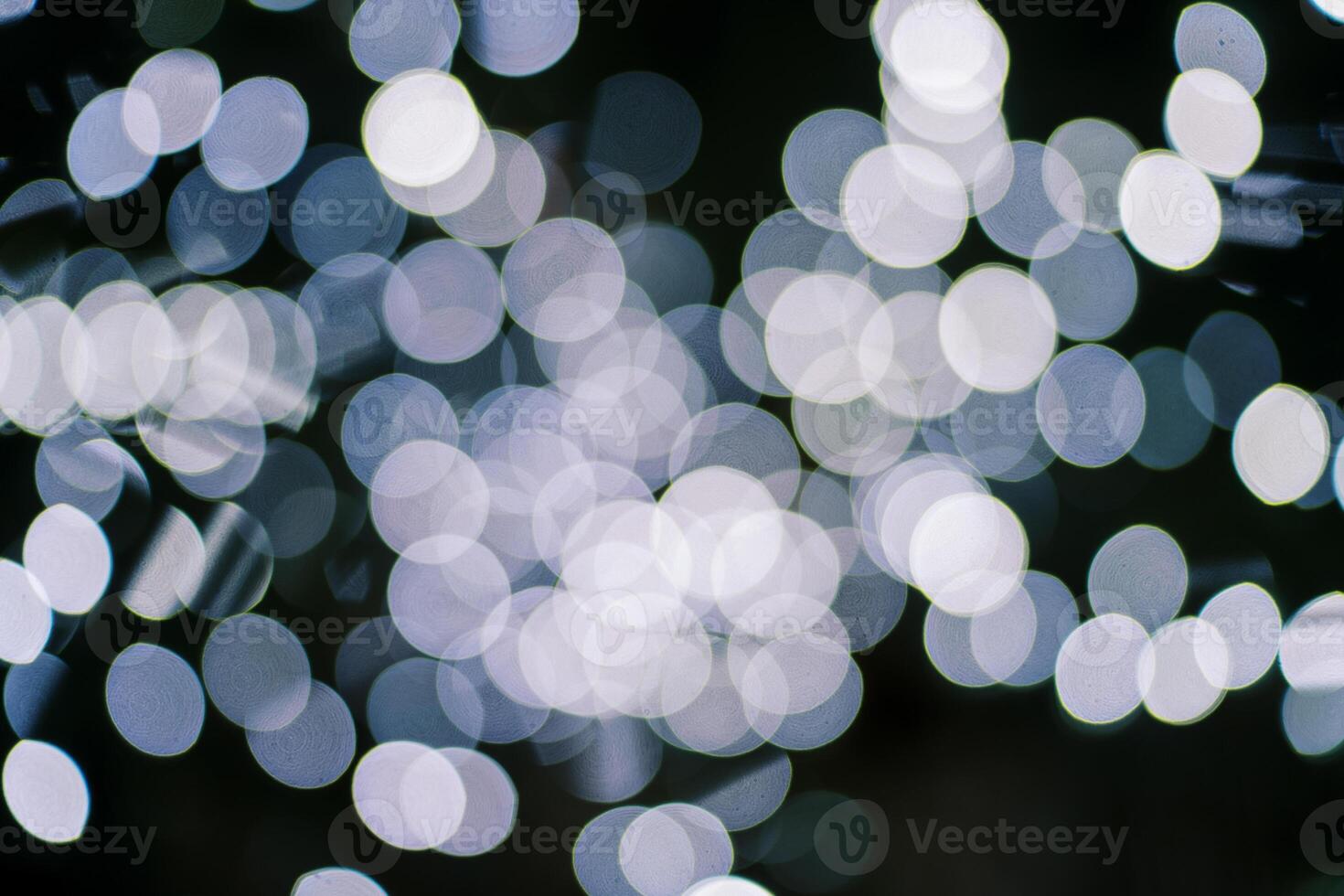 White sparkling round lights on a dark background. Blur photo