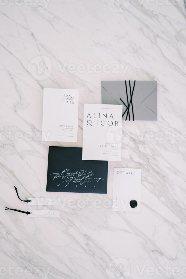 Wedding invitations with name tags lie on a white marble table photo
