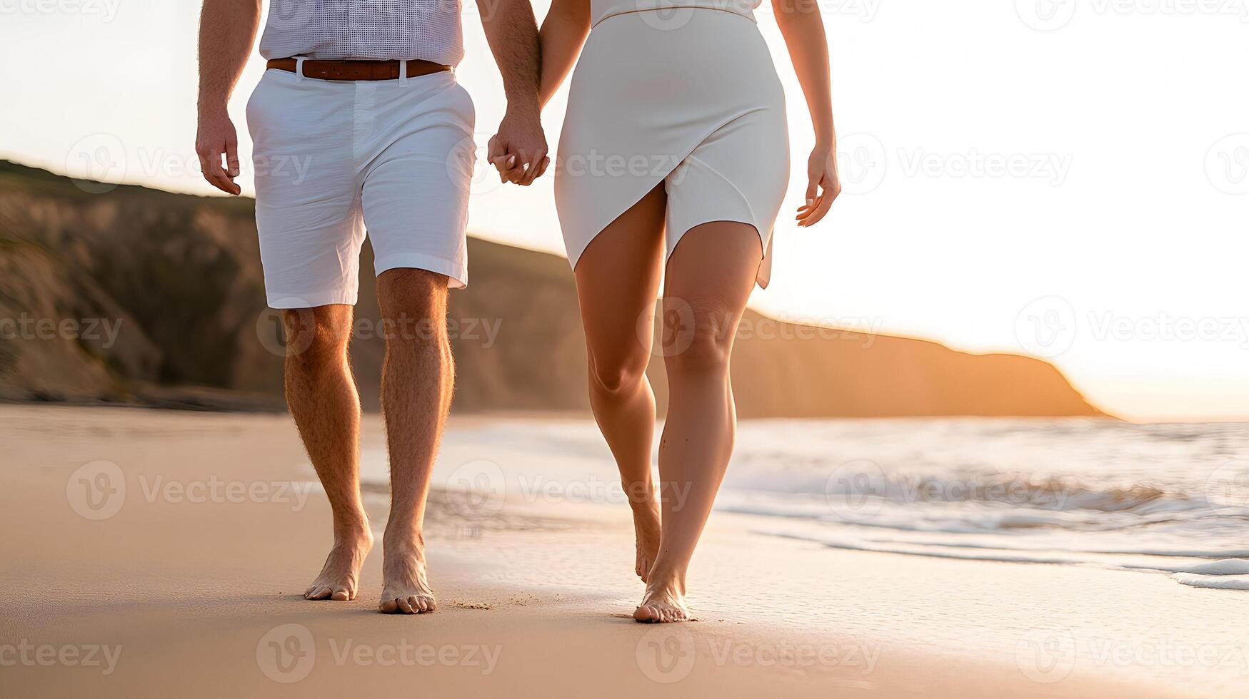 A couple walking hand in hand on a golden beach at sunset, waves gently lapping at their feet photo